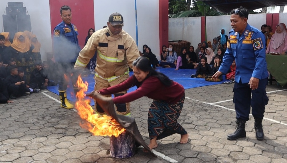 Seorang ibu rujmah tangga mencoba memadamkan api dengan didampingi petugas (foto : istimewa)
